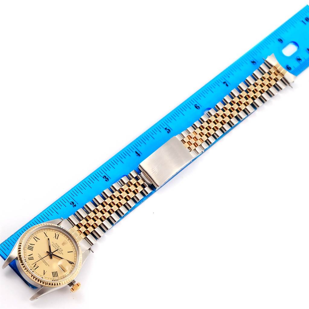 The Rolex Datejust 16013 Men's Stainless Steel Champagne Dial 16013 Men's Stainless Steel Champagne Dial watch shown is laid flat with a blue ruler measuring its two-tone bracelet and gold dial.