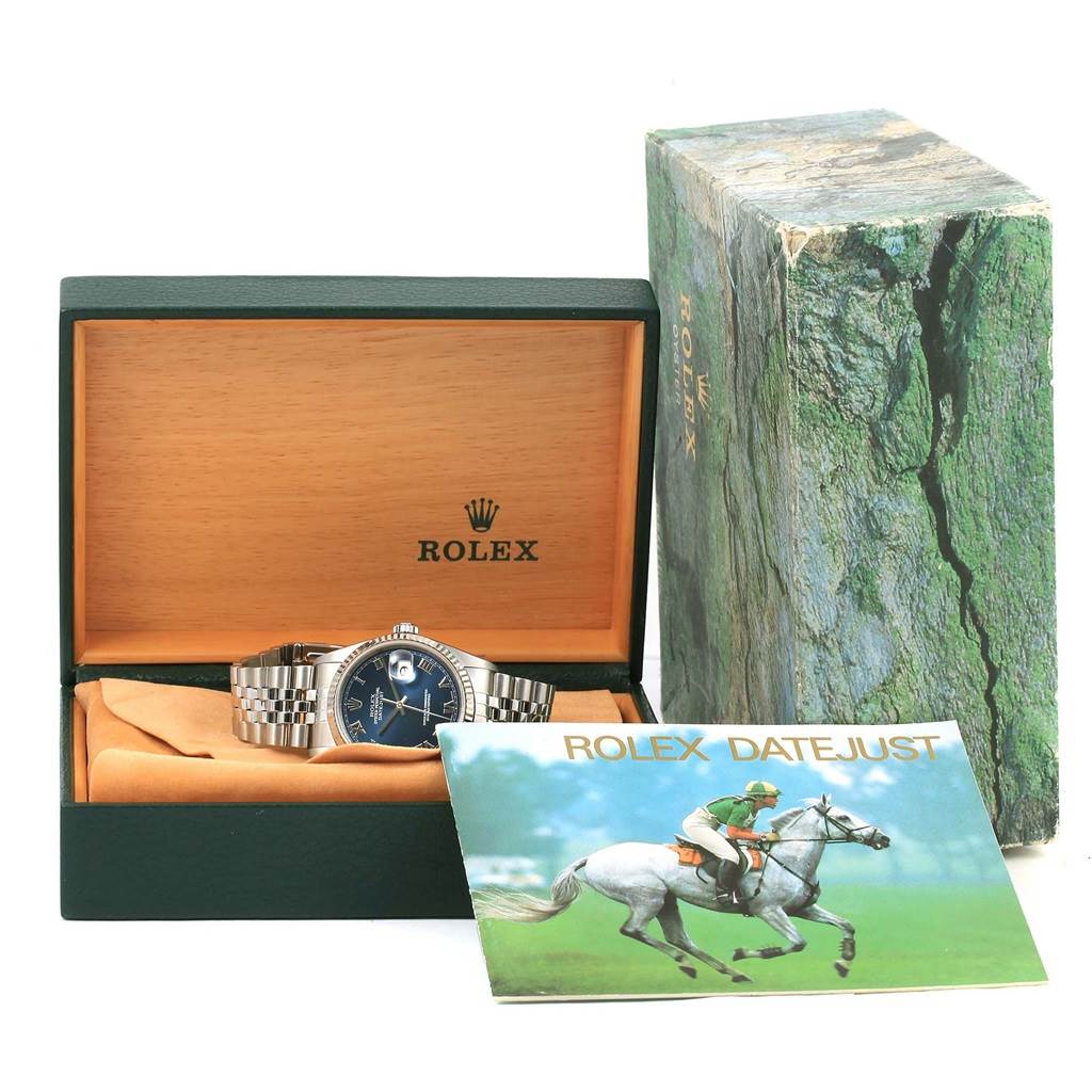 The image shows a Rolex Datejust 16234 Men's Stainless Steel Blue Dial 16234 Men's Stainless Steel Blue Dial watch in its open box, accompanied by a booklet and an outer packaging box.