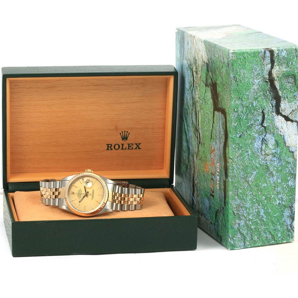 The Rolex Datejust 16233 Men's Steel and Gold (two tone) Champagne Dial 16233 Men's Steel and Gold (two tone) Champagne Dial watch is displayed head-on, situated inside its open green and wood box, with the outer box beside it.