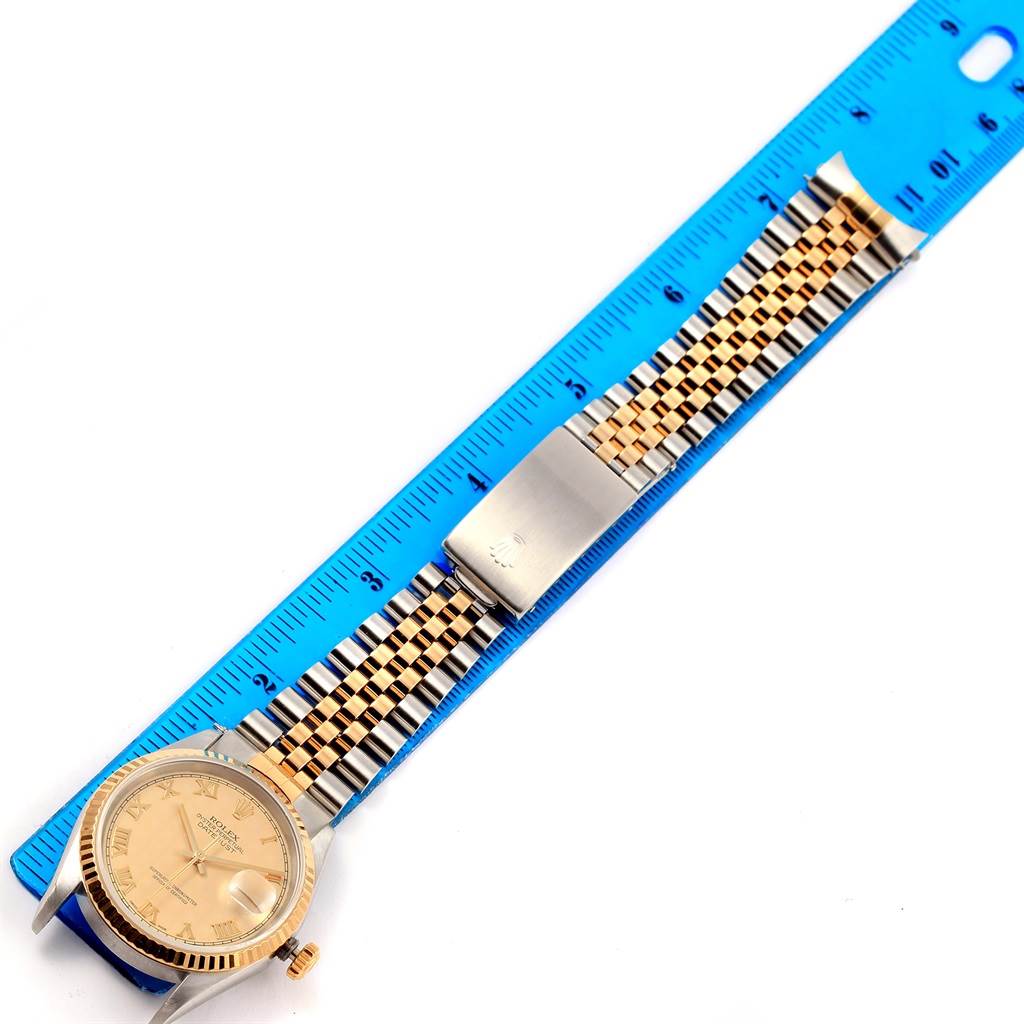 The Rolex Datejust 16233 Men's Steel and Gold (two tone) Beige Dial 16233 Men's Steel and Gold (two tone) Beige Dial watch is shown from a top-down angle, displaying its face, bracelet, and clasp, with a ruler for scale.