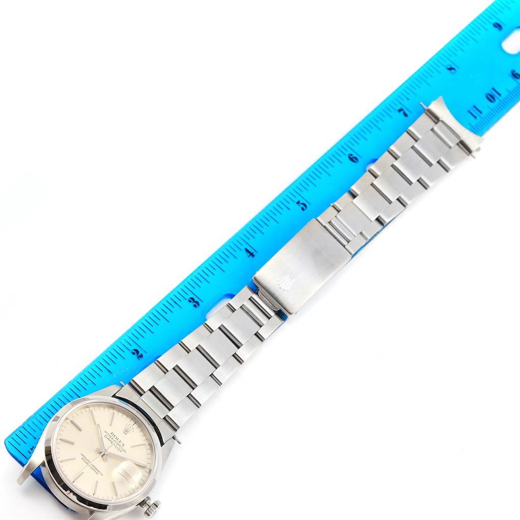 The Rolex Datejust 16200 Men's Stainless Steel Silver Dial 16200 Men's Stainless Steel Silver Dial watch is shown from a top view, displaying its face, bezel, and full bracelet beside a blue ruler for scale.