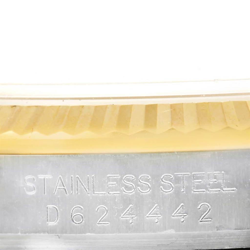 This close-up image of a Rolex Datejust 116233 Men's Stainless Steel White Dial 116233 Men's Stainless Steel White Dial watch shows part of the fluted bezel and the stainless-steel case with its serial number.