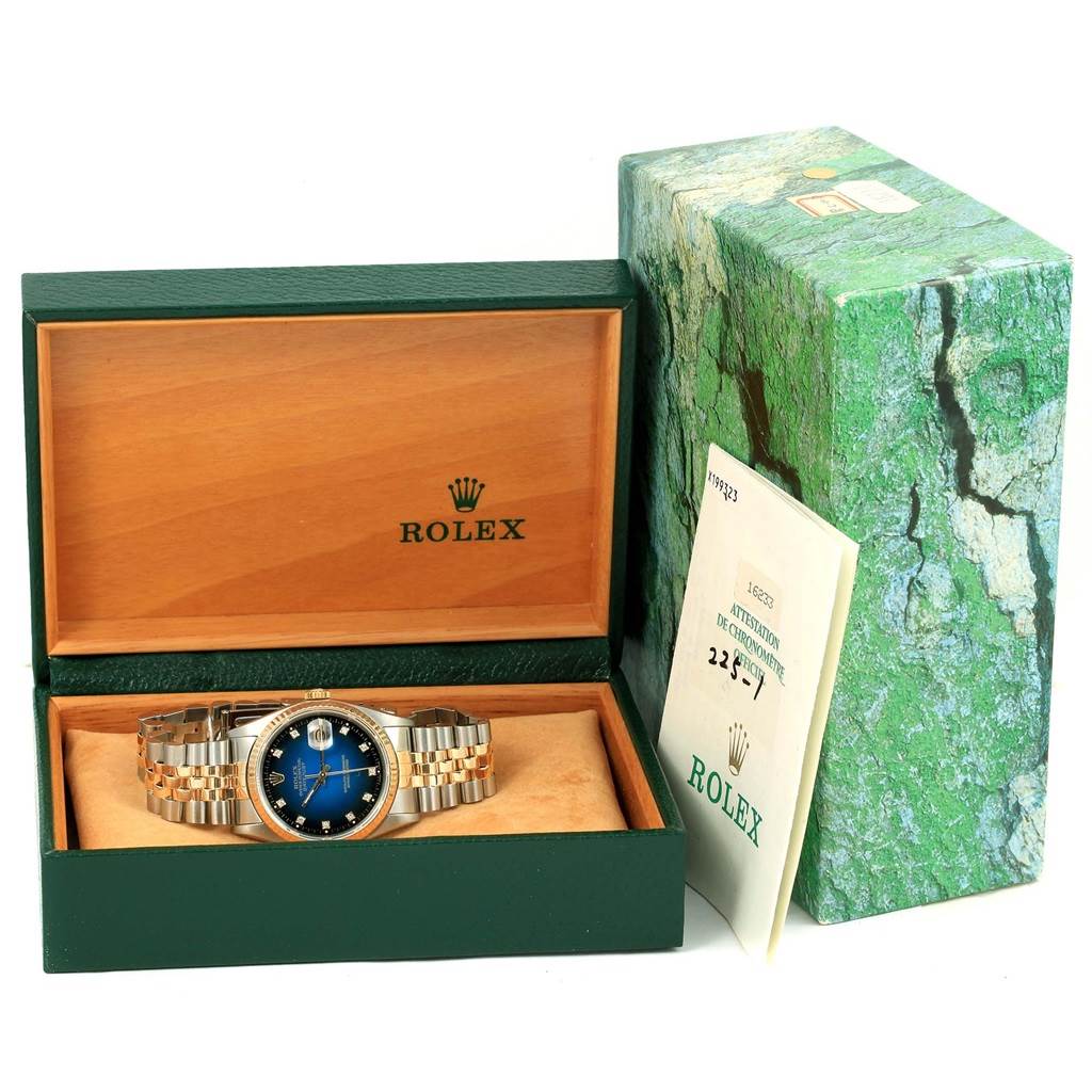 The Rolex Datejust 16233 Men's Steel and Gold (two tone) Blue Dial 16233 Men's Steel and Gold (two tone) Blue Dial watch is displayed in an open box at a slight angle, with its bracelet, case, and dial visible, alongside its box and papers.