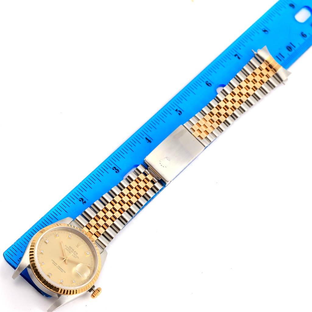 The Rolex Datejust 16233 Steel and Gold (two tone) Champagne Dial 16233 Steel and Gold (two tone) Champagne Dial watch is shown from a top-down angle, displaying the face, crown, and entire bracelet on a blue ruler.