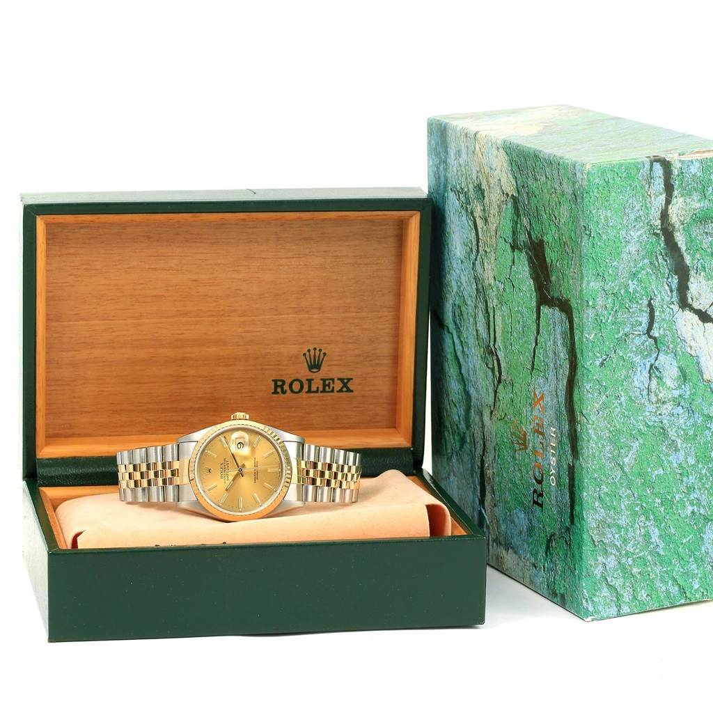 The Rolex Datejust 16233 Men's Steel and Gold (two tone) Champagne Dial 16233 Men's Steel and Gold (two tone) Champagne Dial watch is shown from the front, inside an open green and wooden presentation box, with its outer packaging beside it.