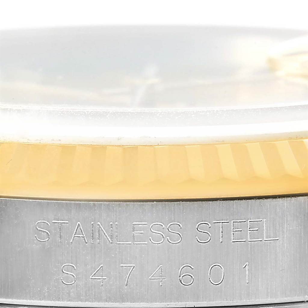 This image shows a close-up side view of a Rolex Datejust 16233 Men's Steel and Gold (two tone) Champagne Dial 16233 Men's Steel and Gold (two tone) Champagne Dial watch, highlighting the bezel and part of the stainless steel case with its serial number.