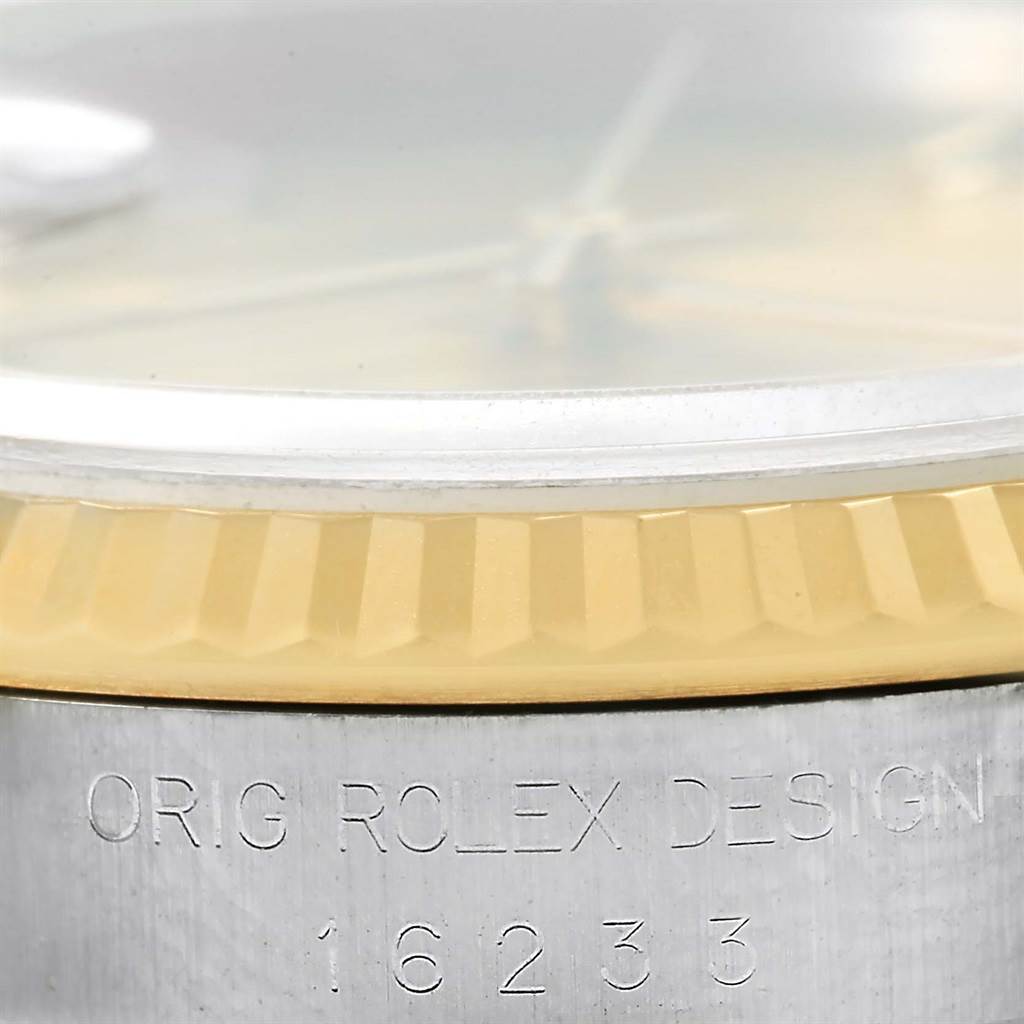 The image shows a close-up of a Rolex Datejust 16233 Men's Steel and Gold (two tone) Champagne Dial 16233 Men's Steel and Gold (two tone) Champagne Dial model's bezel and part of the case, focusing on inscriptions and serrated bezel design.