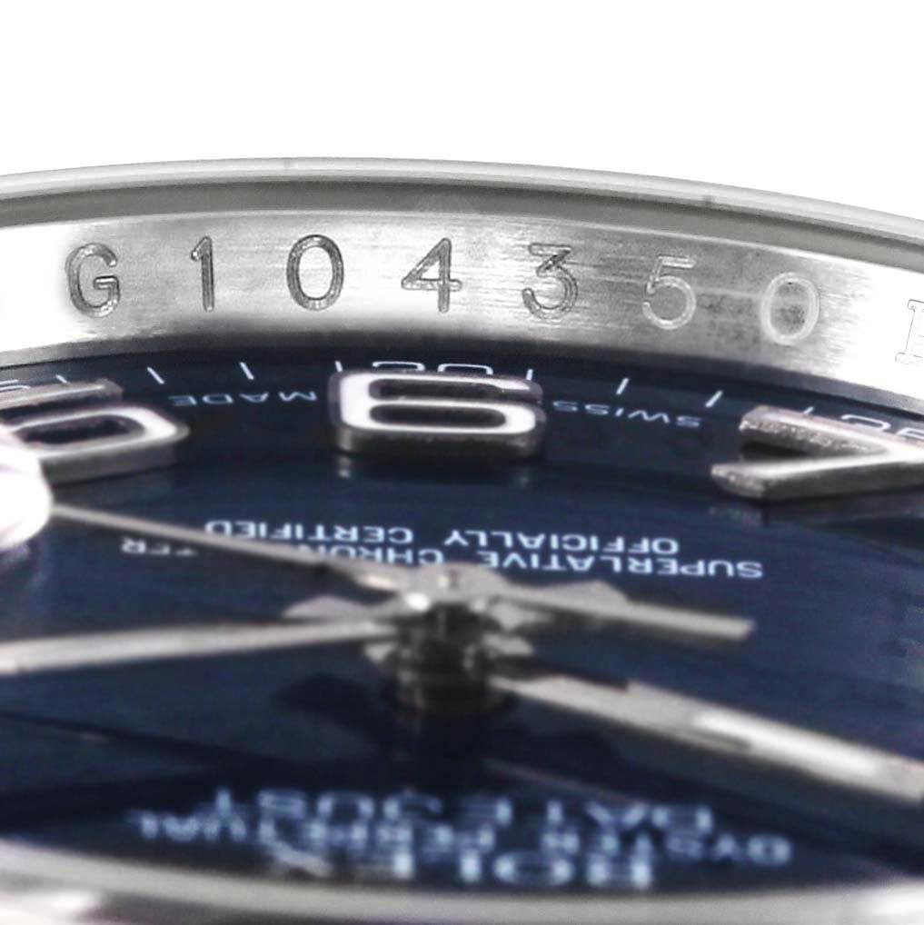 This close-up image of the Rolex Datejust 116234 Men
s Stainless Steel Blue Dial 116234 Men
s Stainless Steel Blue Dial watch focuses on the serial number engraving and part of the watch dial.