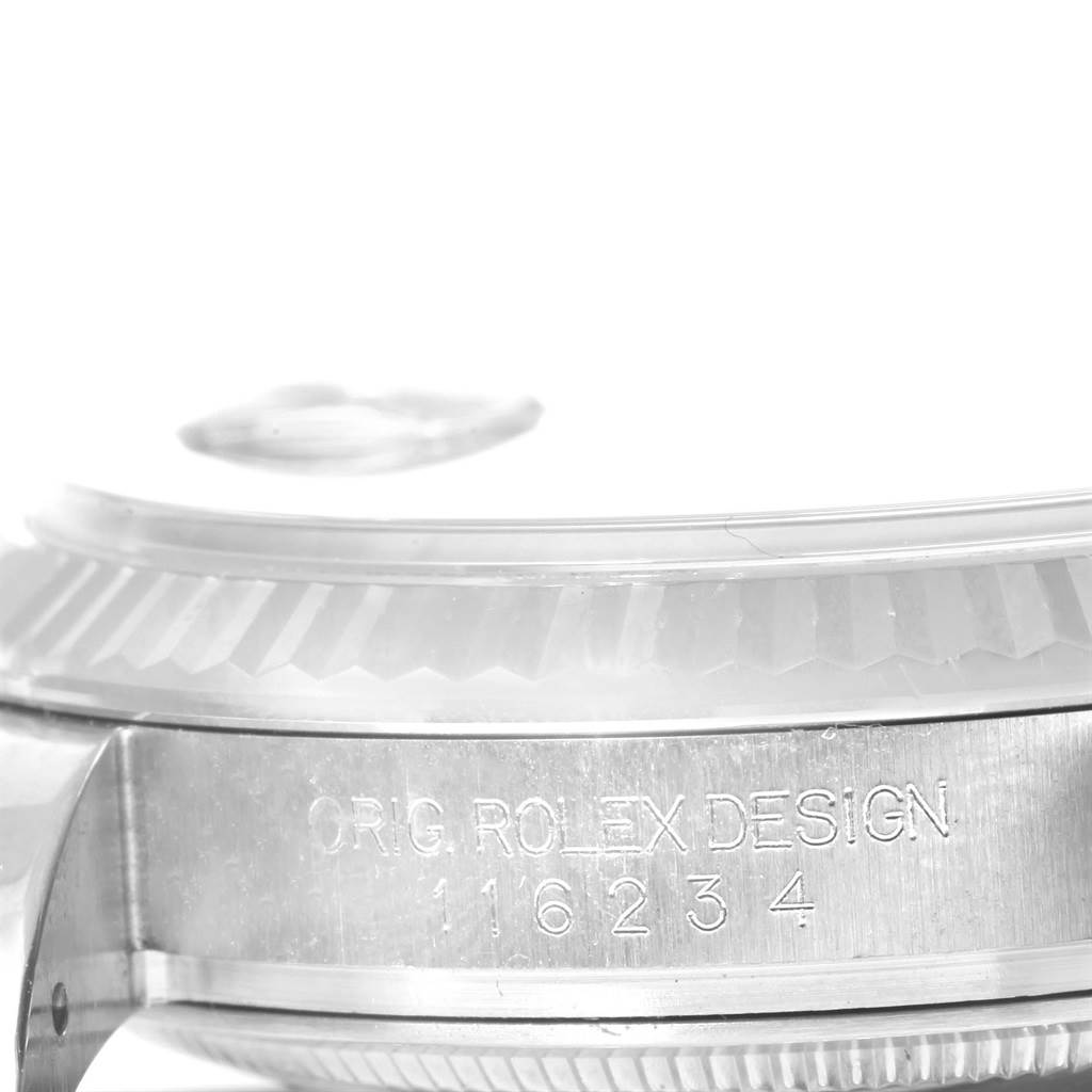 The image shows a close-up of the side of a Rolex Datejust 116234 Men
s Stainless Steel Blue Dial 116234 Men
s Stainless Steel Blue Dial watch, highlighting its serial number and fluted bezel.