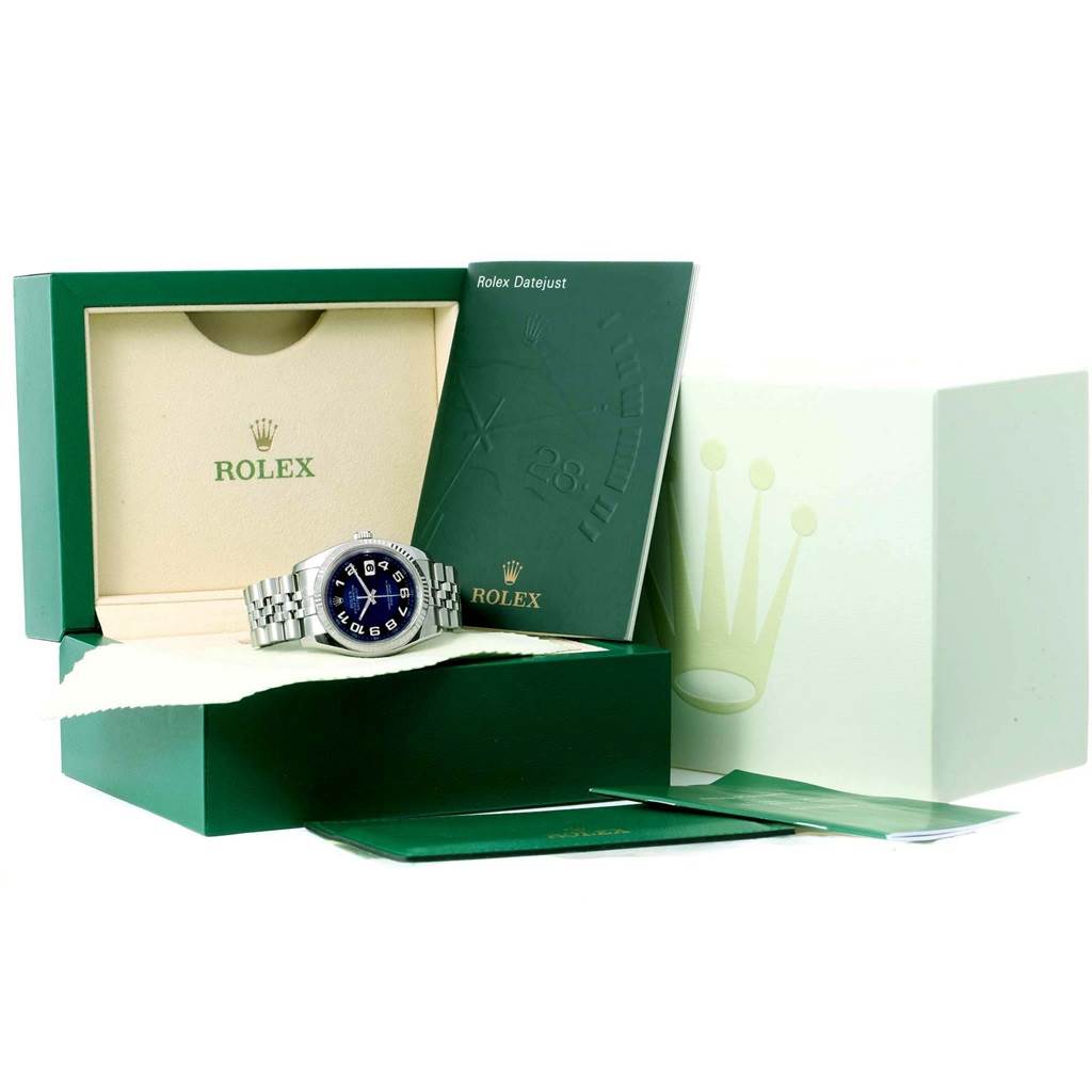 The image shows a Rolex Datejust 116234 Men
s Stainless Steel Blue Dial 116234 Men
s Stainless Steel Blue Dial watch with blue dial set inside its green box, along with booklets and accessories.