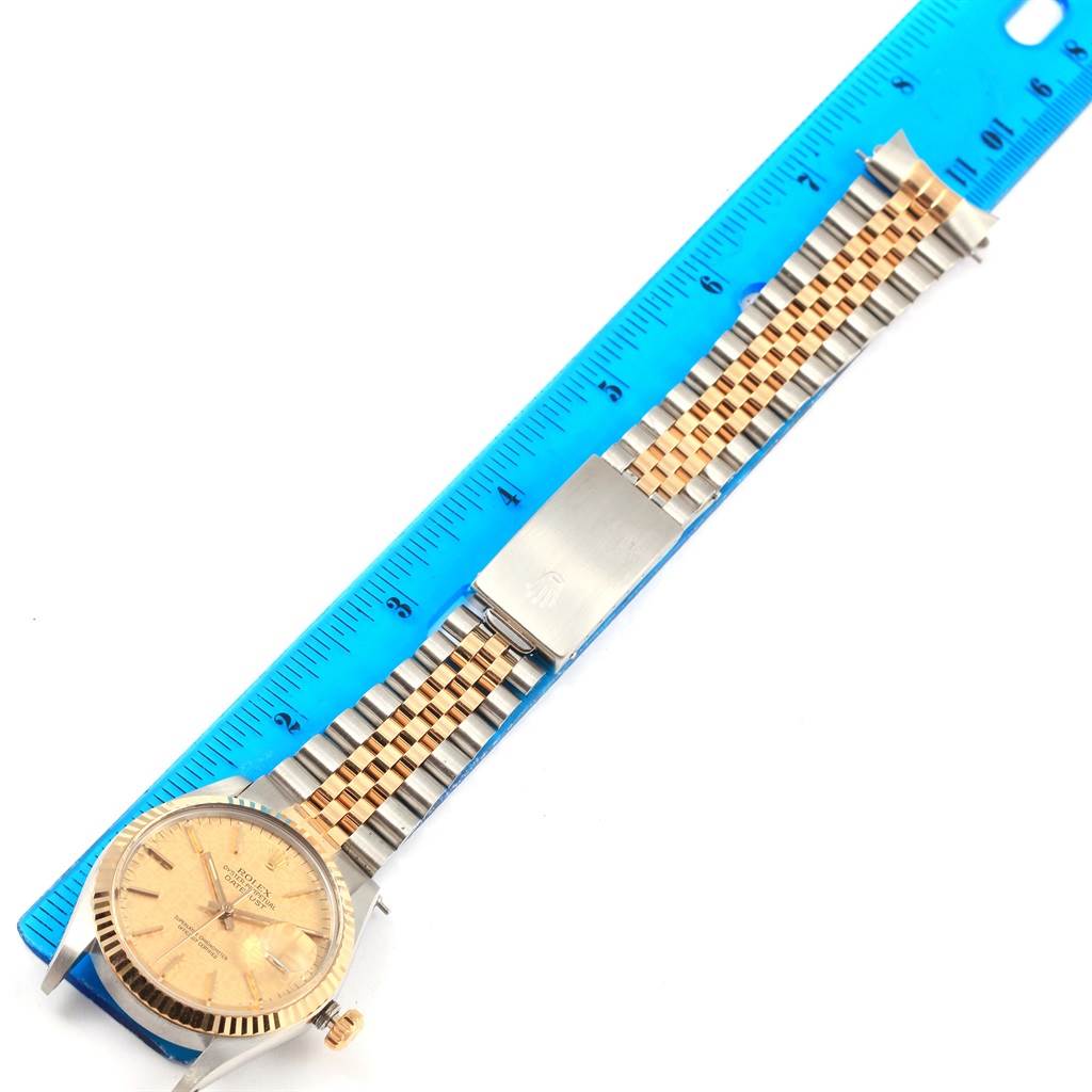 This image shows a Rolex Datejust 16013 Men's Stainless Steel Champagne Dial 16013 Men's Stainless Steel Champagne Dial watch laid flat with a blue ruler, displaying the face, crown, and bi-tone bracelet.