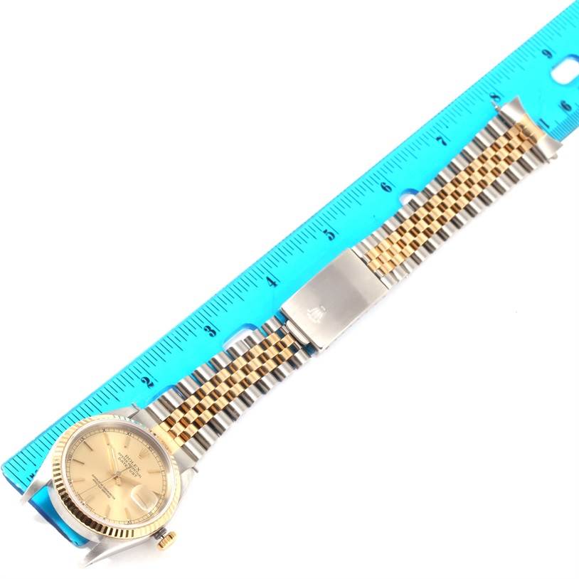 The image shows a Rolex Datejust 16233 Men's Steel and Gold (two tone) Champagne Dial 16233 Men's Steel and Gold (two tone) Champagne Dial watch laid flat next to a ruler, highlighting the two-tone band and face.