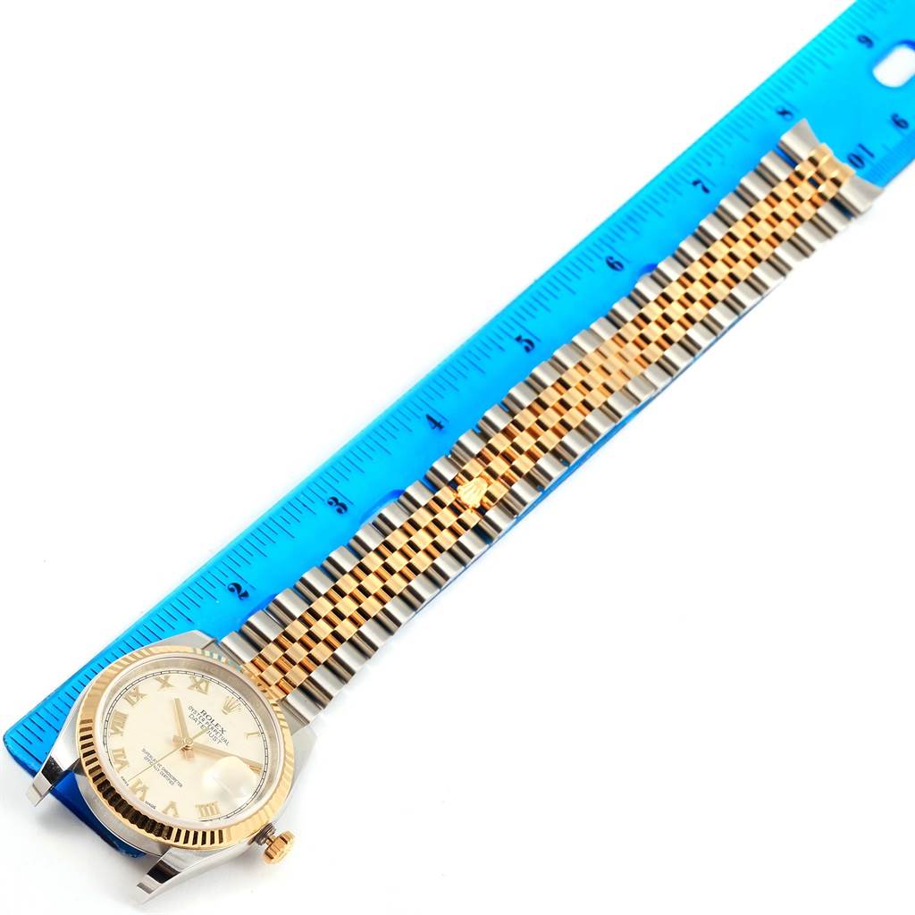 The image shows the Rolex Datejust 116233 Men's Stainless Steel Beige Dial 116233 Men's Stainless Steel Beige Dial watch from a top-down angle, highlighting the face and bracelet next to a blue ruler for scale.