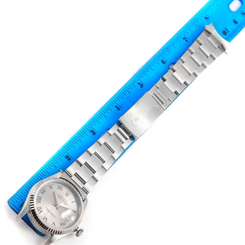 The image shows a top view of a Rolex Datejust 16234 Men's Stainless Steel Silver Dial 16234 Men's Stainless Steel Silver Dial watch laid against a blue ruler, displaying the watch face and metal bracelet.