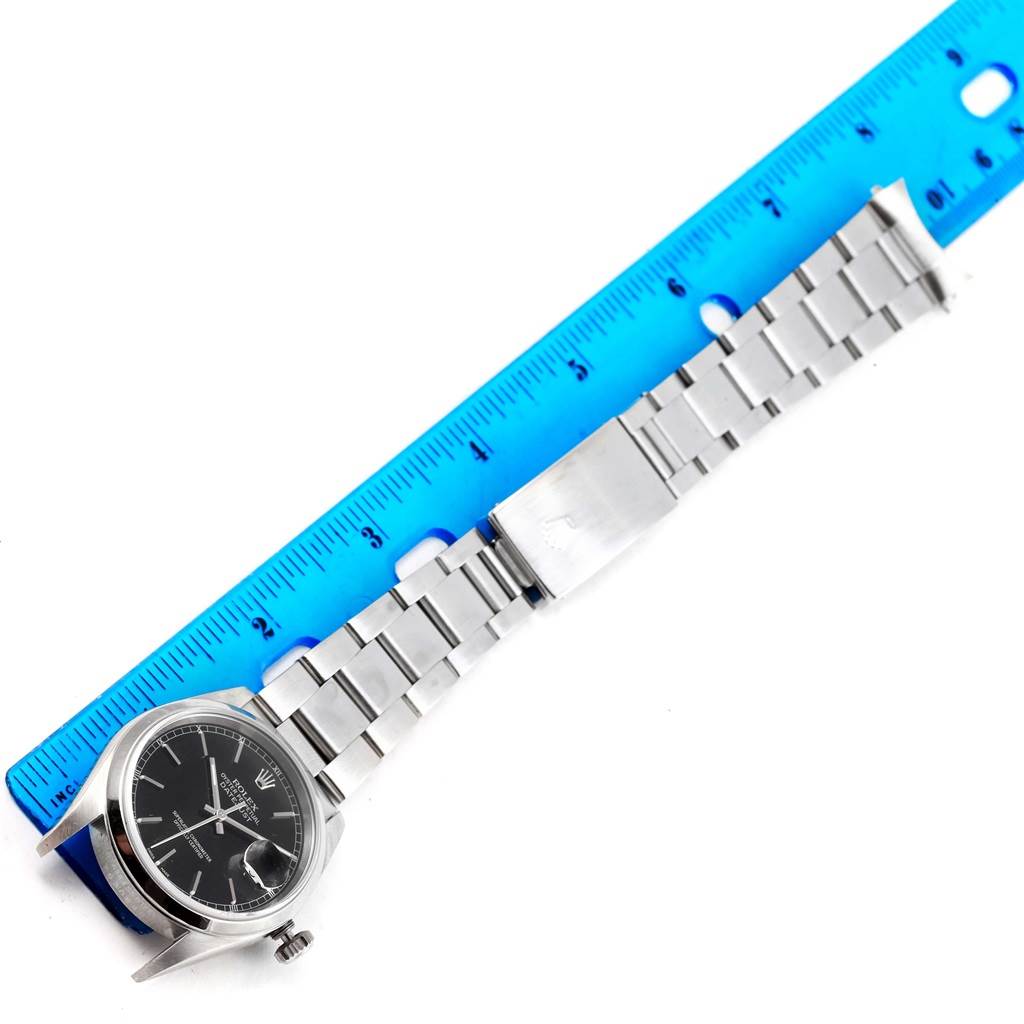 This image shows a Rolex Datejust 16200 Men's Stainless Steel Black Dial 16200 Men's Stainless Steel Black Dial watch laid flat with a blue ruler for scale.