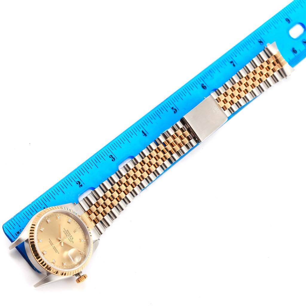 The image shows a Rolex Datejust 16233 Men's Steel and Gold (two tone) Champagne Dial 16233 Men's Steel and Gold (two tone) Champagne Dial watch laid flat with its bracelet extended beside a blue ruler for scale.