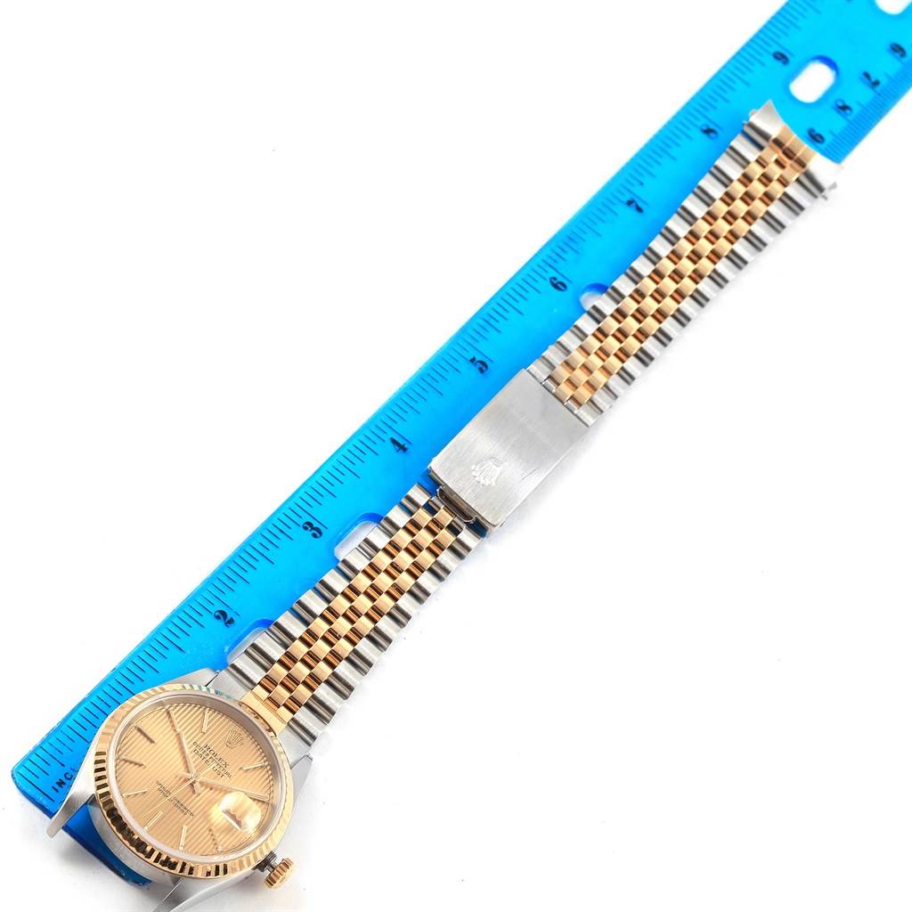 This image shows a Rolex Datejust 16233 Men's Steel and Gold (two tone) Champagne Dial 16233 Men's Steel and Gold (two tone) Champagne Dial watch laid flat with a blue ruler measuring its length.