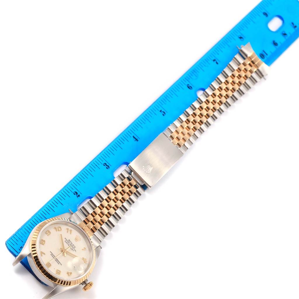 The image shows a Rolex Datejust 16233 Men's Steel and Gold (two tone) Beige Dial 16233 Men's Steel and Gold (two tone) Beige Dial watch, including the face and two-tone metal bracelet, laid next to a blue ruler for scale.