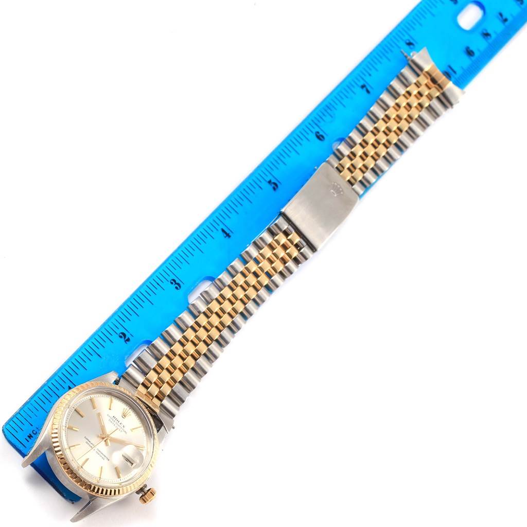 The Rolex Datejust 1601 Men's Stainless Steel Silver Dial 1601 Men's Stainless Steel Silver Dial watch is shown from an overhead angle, highlighting the face, bezel, and two-tone bracelet next to a ruler.