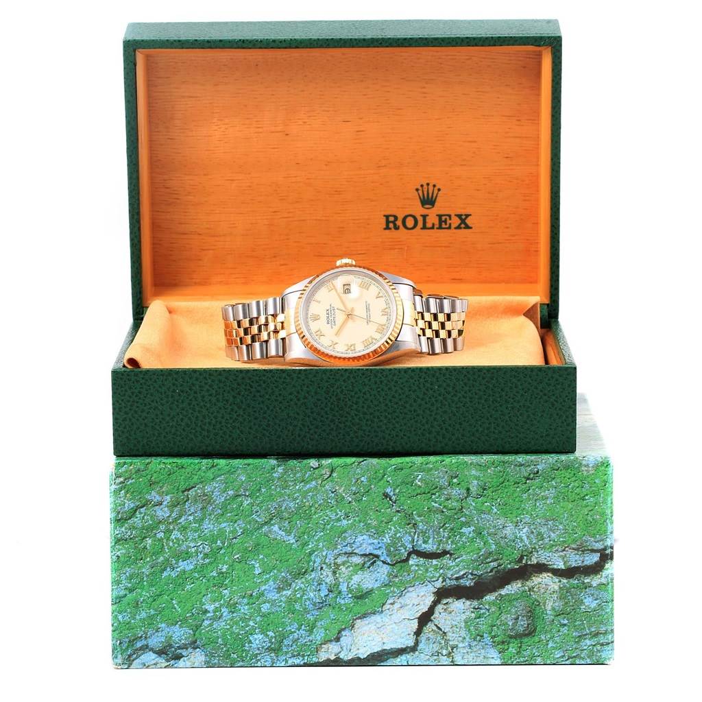 The Datejust Rolex watch is displayed in an open green box, showing its face and bracelet from a front angle.