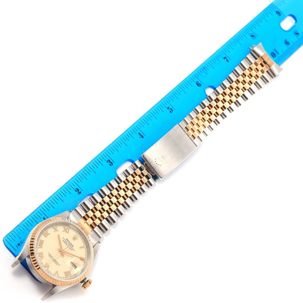 The image shows a Rolex Datejust 16233 Men's Steel and Gold (two tone) Beige Dial 16233 Men's Steel and Gold (two tone) Beige Dial watch laid flat beside a blue ruler, revealing the watch face and metal bracelet.