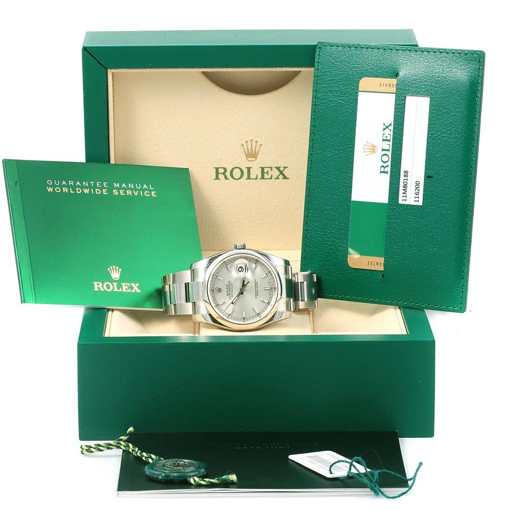 The Rolex Datejust 116200 Men's Stainless Steel Silver Dial 116200 Men's Stainless Steel Silver Dial watch is shown front-facing in its open green box, accompanied by manuals, tags, and a warranty card.