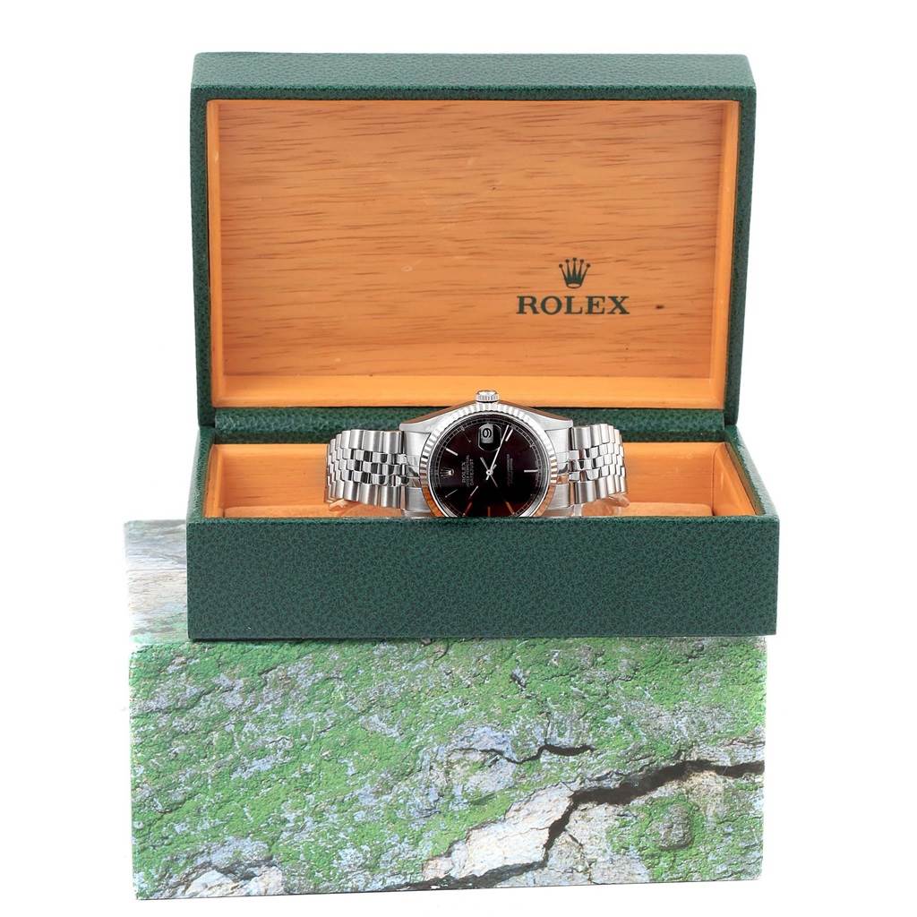 The Rolex Datejust 16234 Men's Stainless Steel Black Dial 16234 Men's Stainless Steel Black Dial watch is displayed frontally in an open green and wood box, showing the face and bracelet.
