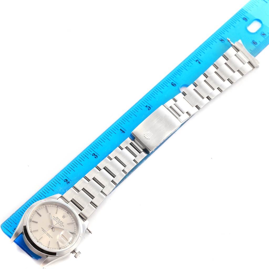 The Rolex Datejust 16220 Men's Stainless Steel Silver Dial 16220 Men's Stainless Steel Silver Dial watch is shown from an overhead angle with its bracelet extended and measured alongside a ruler.