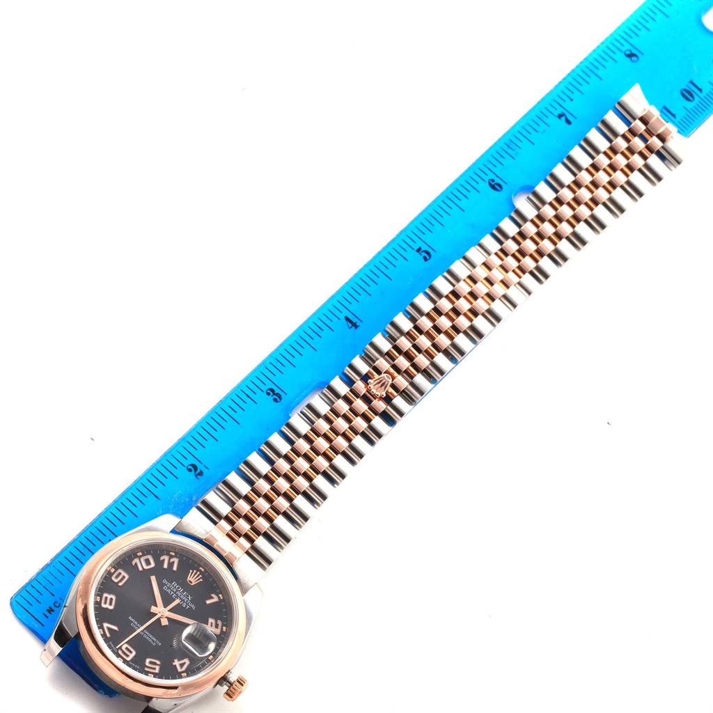 The image shows a top-down view of a Rolex Datejust 116201 Men
s Steel and Gold (two tone) Black Dial 116201 Men
s Steel and Gold (two tone) Black Dial watch with the face, bezel, and bracelet positioned next to a ruler.