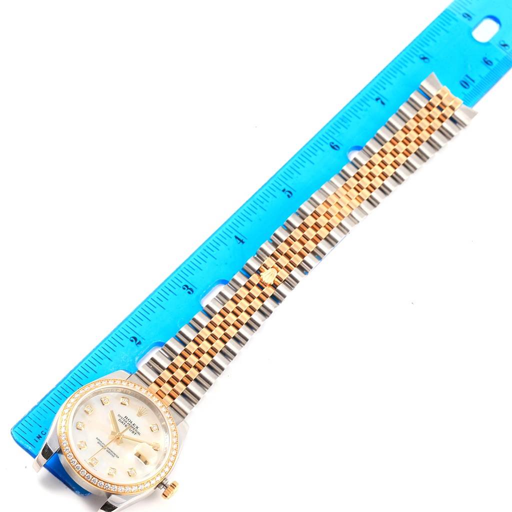 The Rolex Datejust 116243 Men's Stainless Steel Mother of Pearl Dial 116243 Men's Stainless Steel Mother of Pearl Dial watch is shown flat with a blue ruler measuring its length, displaying the face and band.