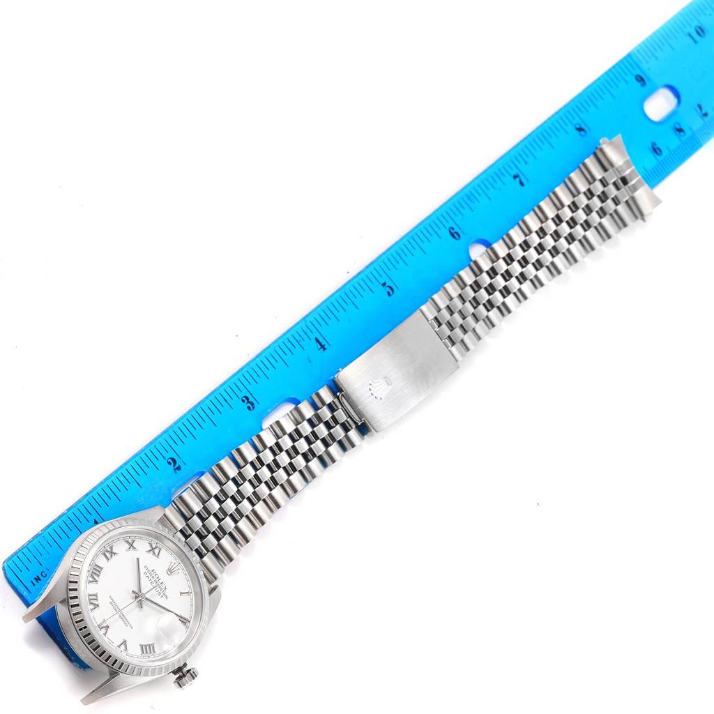 The image shows a Rolex Datejust 16220 Men's Stainless Steel White Dial 16220 Men's Stainless Steel White Dial watch's face and strap alongside a blue ruler, viewed from above.