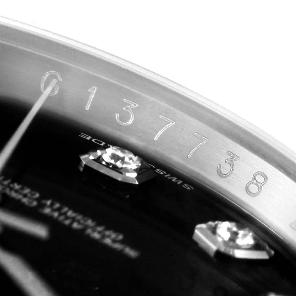 The image shows a close-up angled view of the engraved serial number and diamond markers on the dial of a Rolex Datejust 116244 Stainless Steel Black Dial 116244 Stainless Steel Black Dial watch.