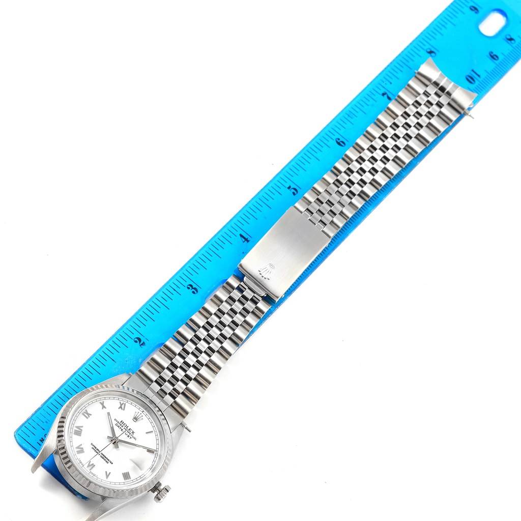 The image shows a top-down view of a Rolex Datejust 16234 Men's Stainless Steel White Dial 16234 Men's Stainless Steel White Dial watch with a metal bracelet next to a blue ruler.