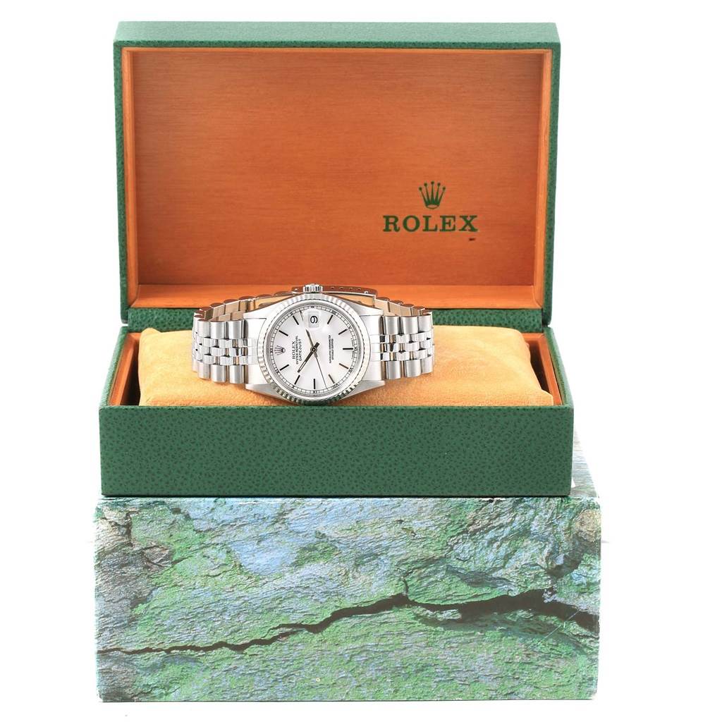 The Rolex Datejust 16234 Men's Stainless Steel White Dial 16234 Men's Stainless Steel White Dial watch is shown from the front, inside an open green and orange box, resting on a cushion.
