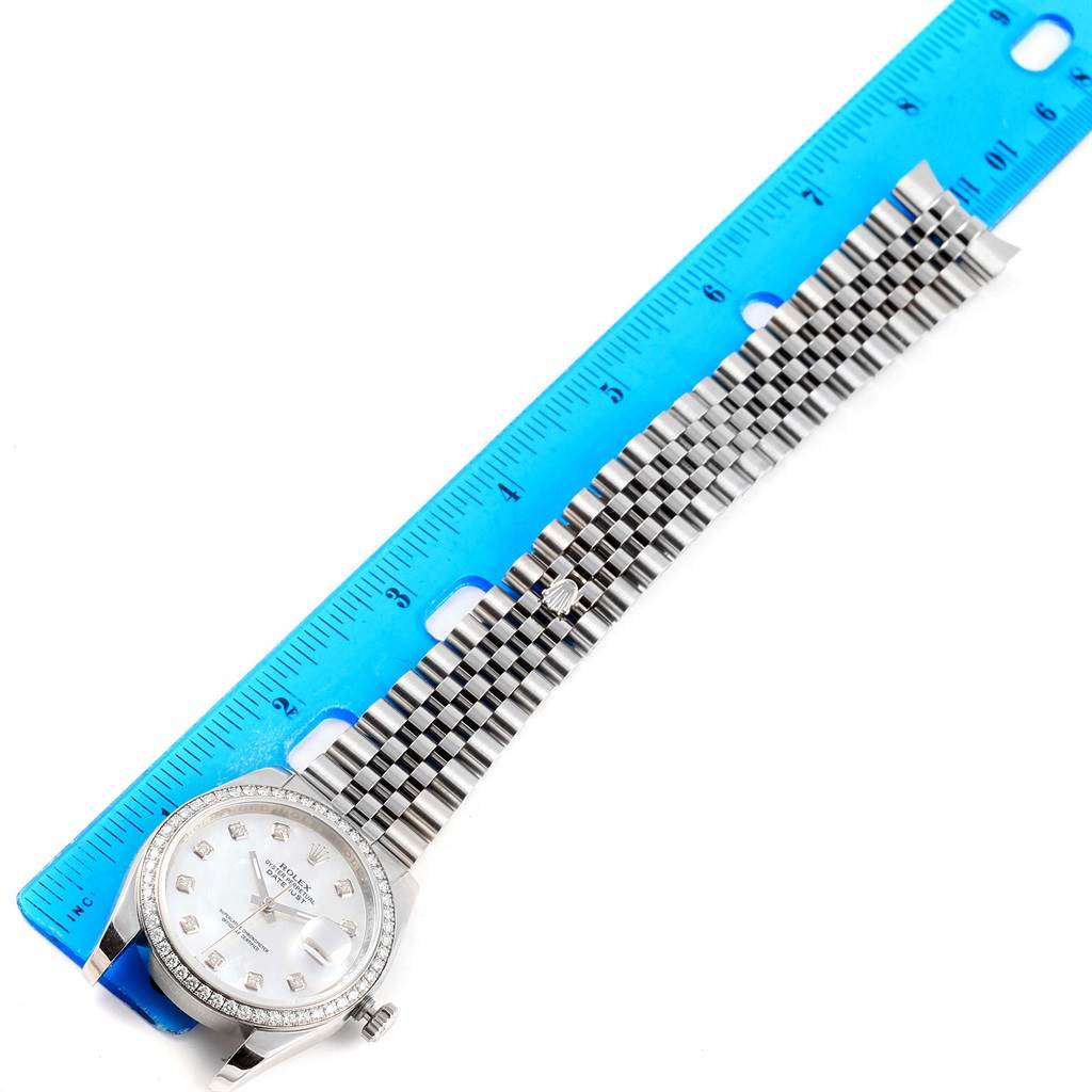 The image shows a Rolex Datejust 116244 Stainless Steel Mother of Pearl Dial 116244 Stainless Steel Mother of Pearl Dial watch with the face and bracelet fully extended beside a blue ruler for measurement.