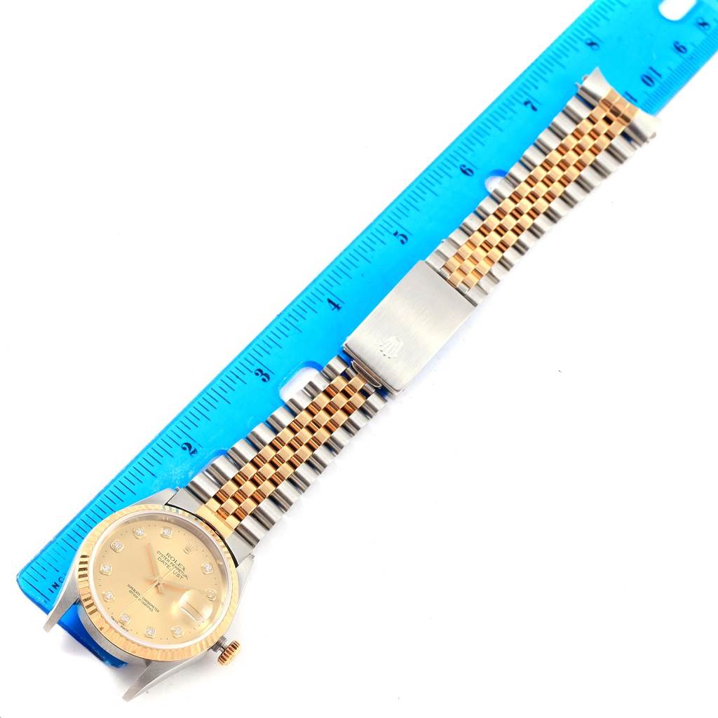This image shows the entire Rolex Datejust 16233 Steel and Gold (two tone) Champagne Dial 16233 Steel and Gold (two tone) Champagne Dial watch, viewed flat with its band extended, placed next to a measuring ruler.