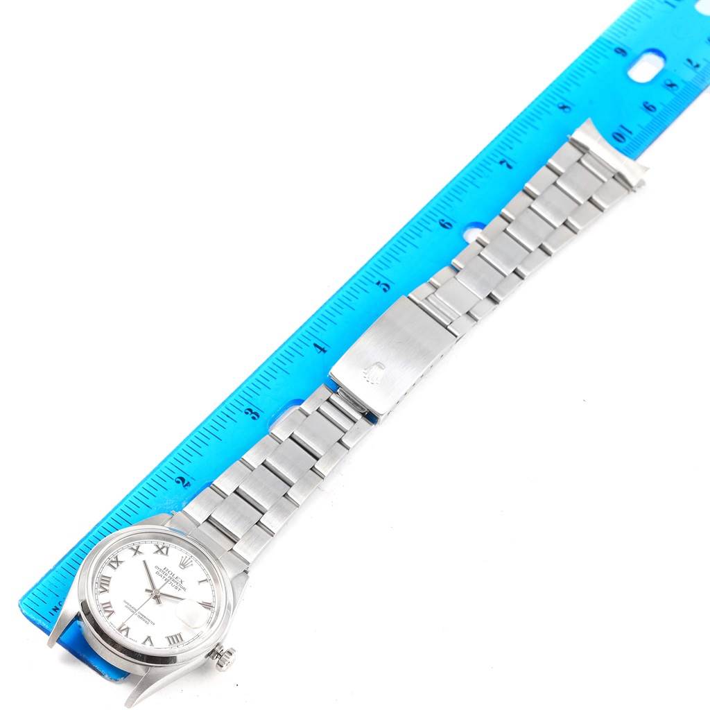 The image shows a top-down view of a Rolex Datejust 16200 Men's Stainless Steel White Dial 16200 Men's Stainless Steel White Dial watch including the face, bracelet, and clasp, along with a blue ruler for scale.