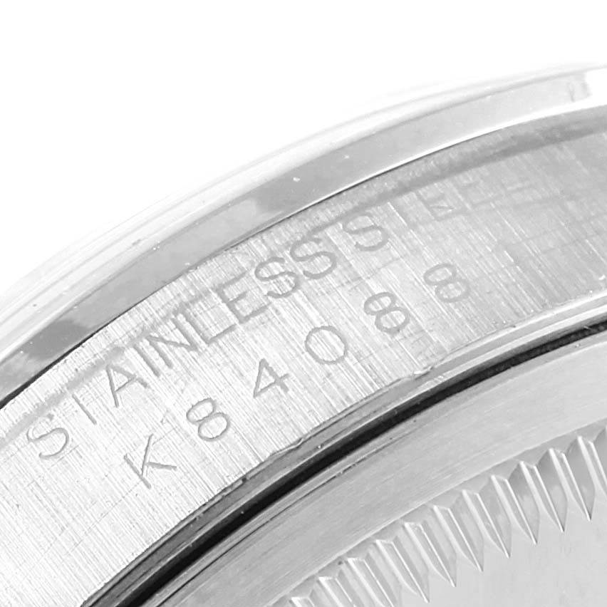 The image shows a close-up of the case back and edge of the bezel of a Rolex Datejust 16200 Men's Stainless Steel White Dial 16200 Men's Stainless Steel White Dial watch, highlighting the serial number and material.