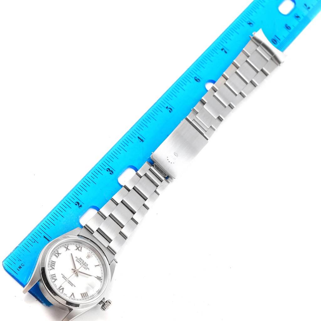 The image shows a top view of a Rolex Datejust 16200 Men's Stainless Steel White Dial 16200 Men's Stainless Steel White Dial watch's face and stainless steel bracelet with a ruler for scale.