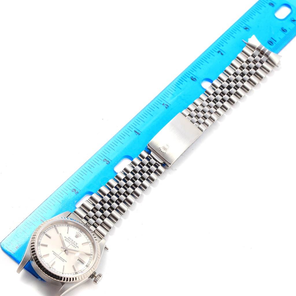 The image shows a top view of a Rolex Datejust 16234 Men's Stainless Steel Silver Dial 16234 Men's Stainless Steel Silver Dial watch and its bracelet next to a blue ruler for size reference.