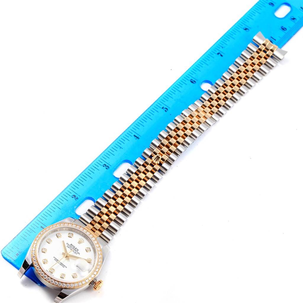 The Rolex Datejust 116243 Stainless Steel White Dial 116243 Stainless Steel White Dial watch is shown from a top-down angle, featuring the face and full length of its two-tone bracelet, along with a measuring ruler.