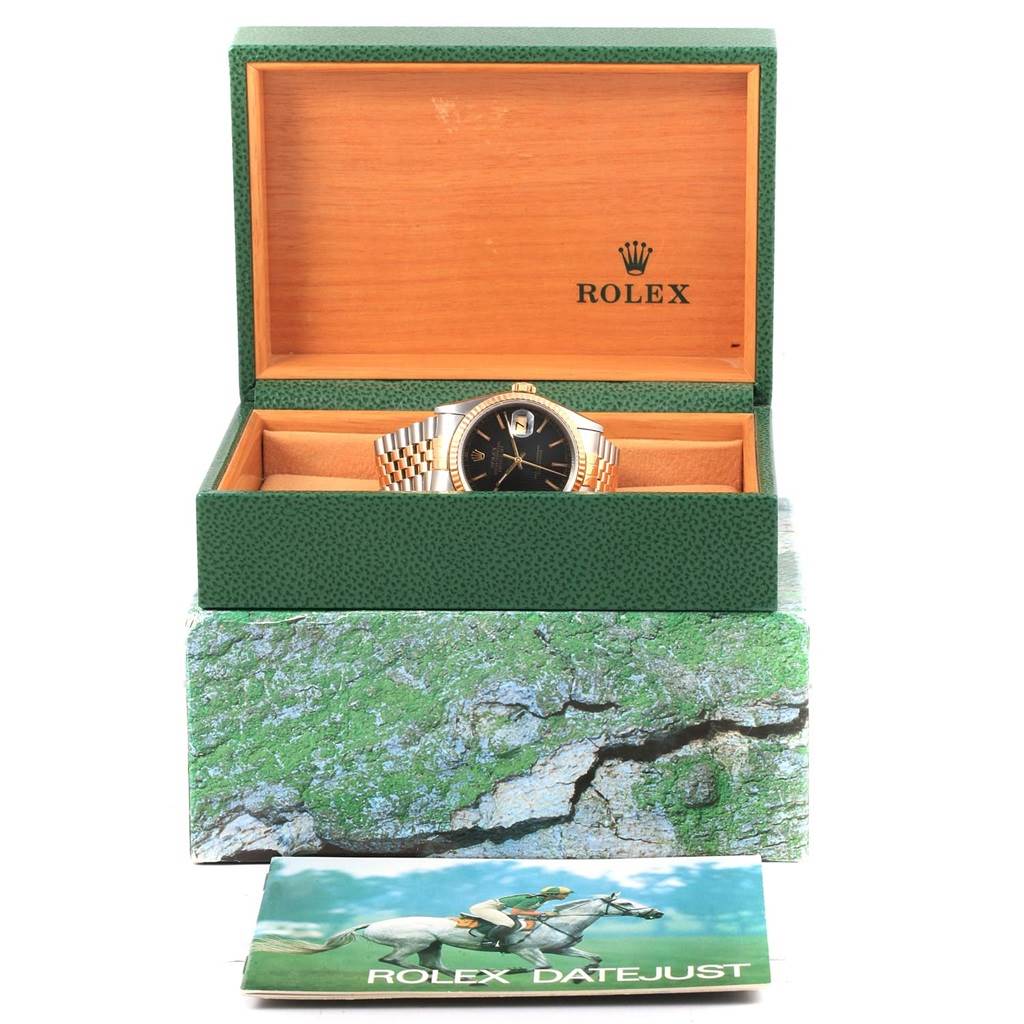 The Rolex Datejust 16233 Men's Steel and Gold (two tone) Black Dial 16233 Men's Steel and Gold (two tone) Black Dial watch is shown in its branded box with its booklet positioned in front.