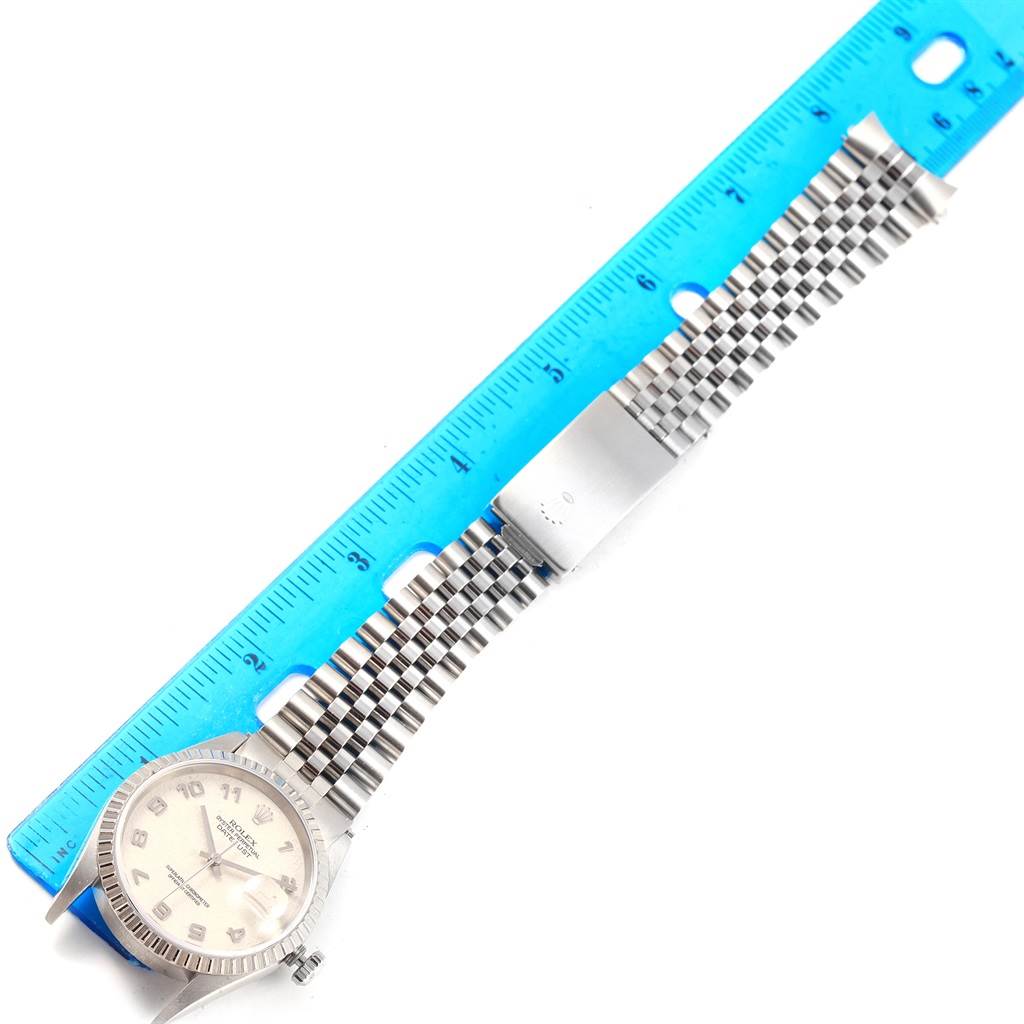 The image shows a top view of a Rolex Datejust 16220 Men's Stainless Steel Silver Dial 16220 Men's Stainless Steel Silver Dial watch with its band measured against a blue ruler.