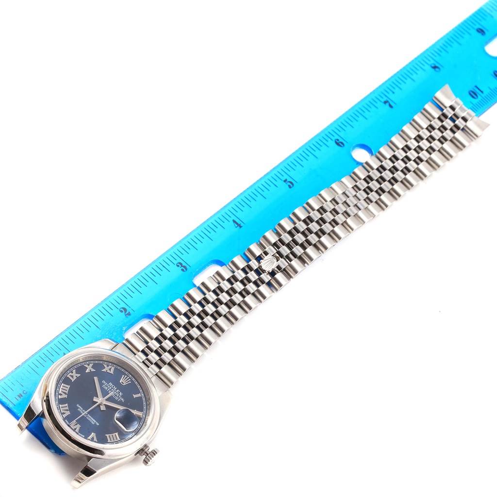 The image shows a top view of a Rolex Datejust 116200 Men's Stainless Steel Blue Dial 116200 Men's Stainless Steel Blue Dial watch, focusing on its face, bezel, and bracelet, with a ruler beside it.