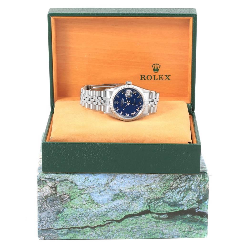 This image shows a Rolex Datejust 16220 Men's Stainless Steel Blue Dial 16220 Men's Stainless Steel Blue Dial watch with a blue dial and Roman numerals, presented inside an open green Rolex box.