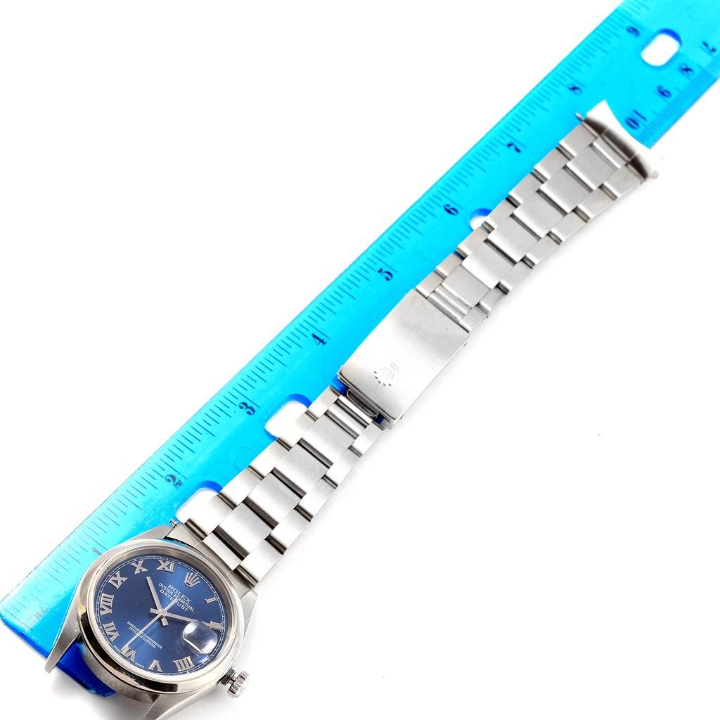 The image shows a top-down view of a Rolex Datejust 16200 Men's Stainless Steel Blue Dial 16200 Men's Stainless Steel Blue Dial watch with a blue dial and a stainless steel bracelet next to a ruler.