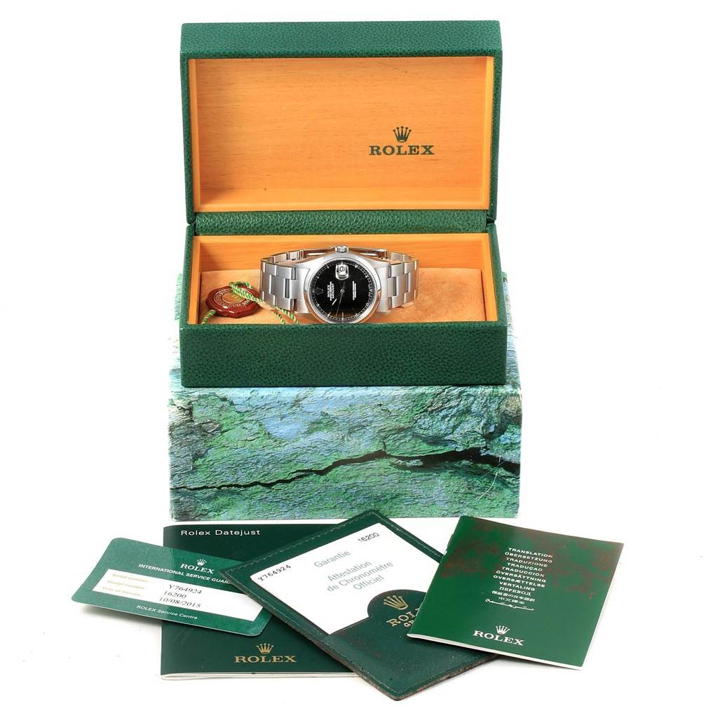The Rolex Datejust 16200 Men's Stainless Steel Black Dial 16200 Men's Stainless Steel Black Dial watch is presented in its open box with booklets and warranty cards shown in front.