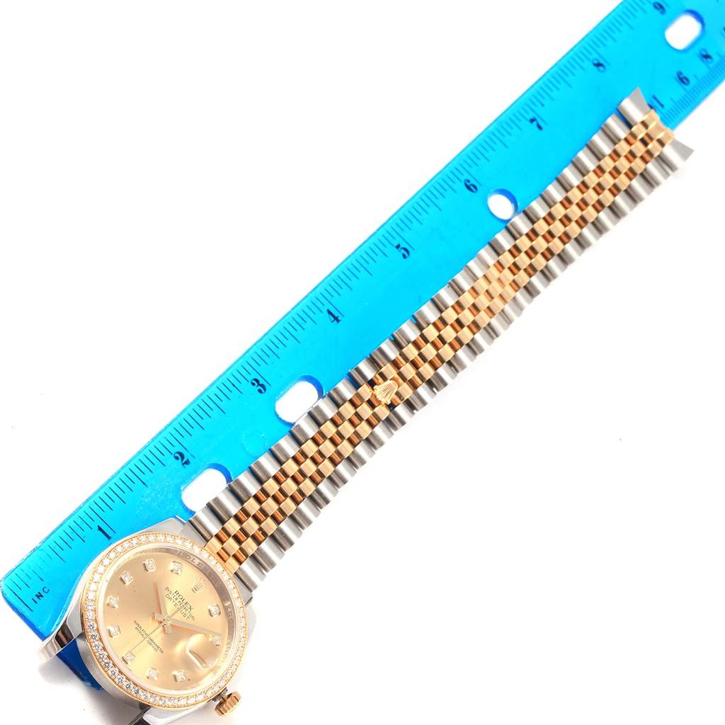 The Rolex Datejust 116243 Women's Stainless Steel Champagne Dial 116243 Women's Stainless Steel Champagne Dial watch is shown from a top view next to a blue ruler, displaying the dial, bezel, and bracelet.