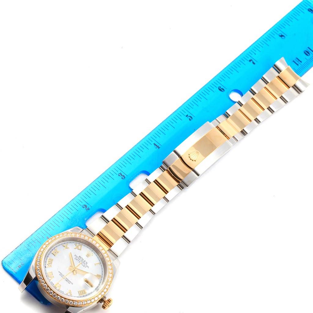 The image shows the Rolex Datejust 116243 Men's Stainless Steel Mother of Pearl Dial 116243 Men's Stainless Steel Mother of Pearl Dial watch, displaying its face, bezel, and band with a blue ruler for scale.