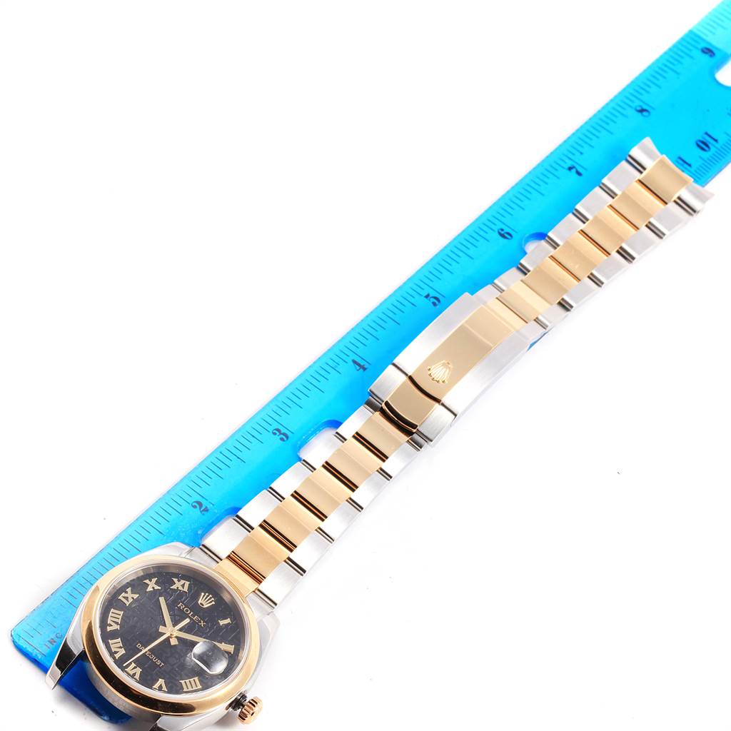 The image shows a Rolex Datejust 116203 Men's Steel and Gold (two tone) Black Dial 116203 Men's Steel and Gold (two tone) Black Dial watch laid flat next to a blue ruler, displaying the watch face and band in full view.